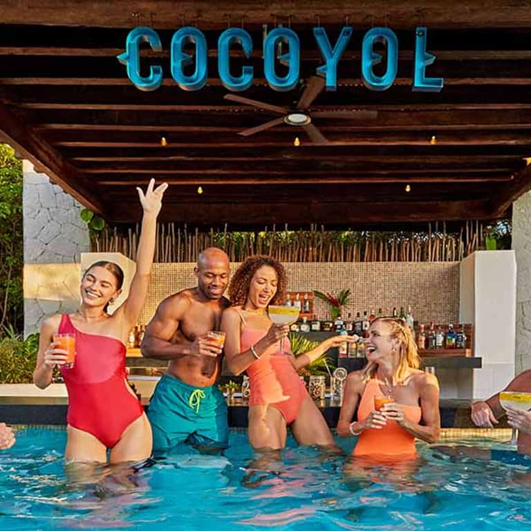 Grupo de amigos brindando en la alberca del bar Cocoyol en Jungala Aqua Experience