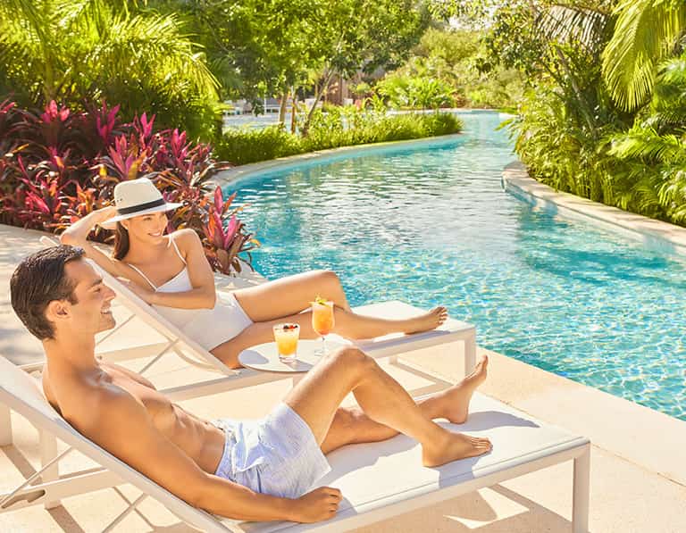 Pareja relajándose en camastros junto al río lento de Jungala Aqua Experience
