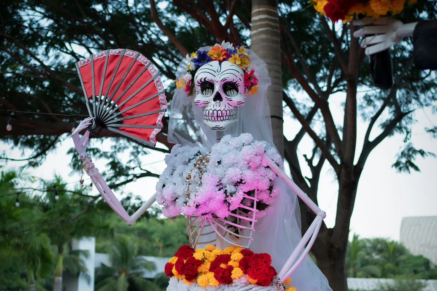 Catrina sculpture dressed in flowers holding a fan