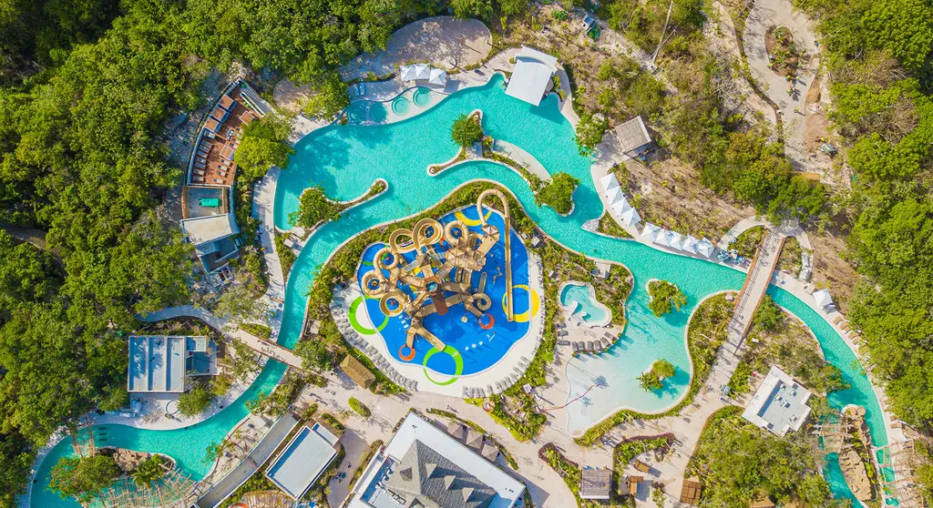 Vista aérea de las atracciones de Jungala Riviera Maya, con río lento, alberca y juegos infantiles rodeados de vegetación