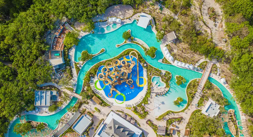 Vista aérea de las atracciones de Jungala Riviera Maya, con río lento, alberca y juegos infantiles rodeados de vegetación