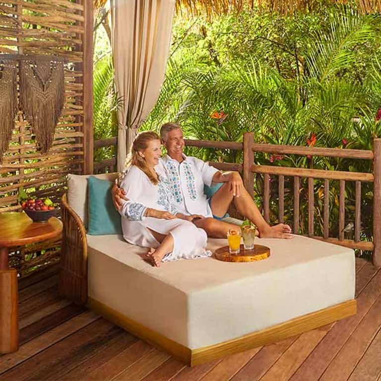 Pareja sentada en la cama de una cabaña privada de Jungala Aqua Experience