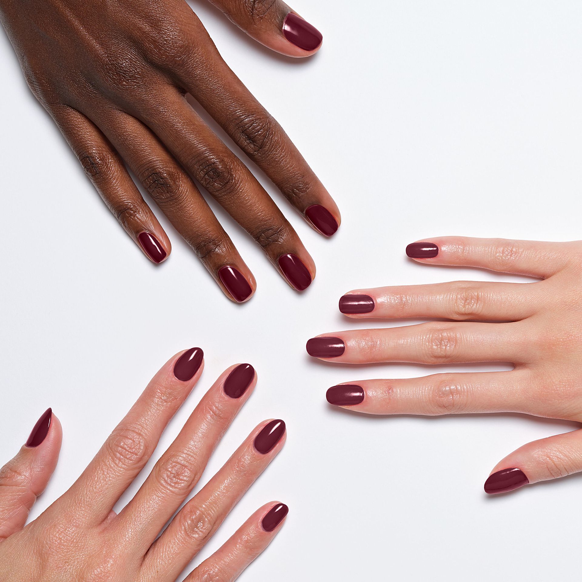 Three models' hands with different skin tones showcasing Sally Hansen Miracle Gel Supercharged Bold Glam in Downtown Rush 490, a deep wine creme nail colour