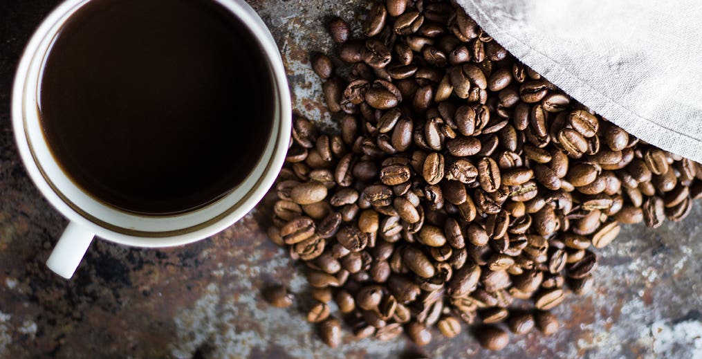 overhead shot of cup of coffee and coffee beans