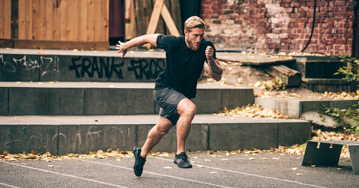 man in black shirt and gray shorts doing sprints outside