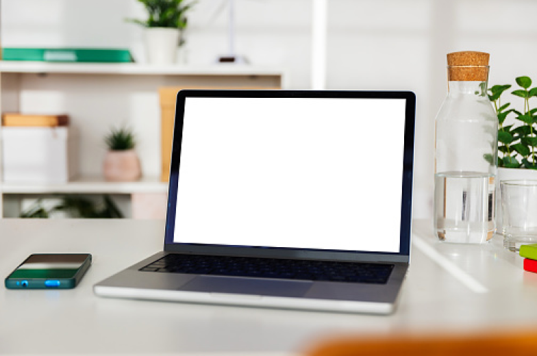 Laptop with a blank screen shown on a desk in a room with all sorts of trinkets and decor