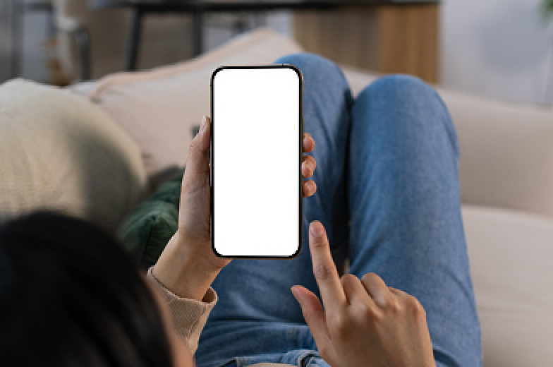 Phone with a blank screen shown being used in someone's hand while they are laying on the couch in a living room