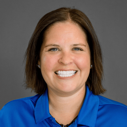 A person with shoulder-length hair wearing a blue collared shirt, with their face blurred out, set against a plain background. A person with shoulder-length hair wearing a blue collared shirt, with their face blurred out, set against a plain background.
