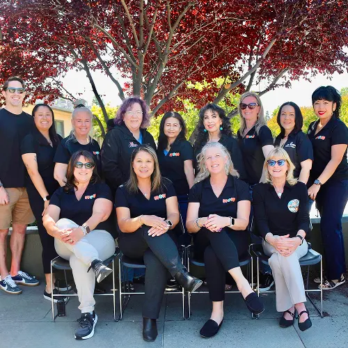 A group of individuals posing outdoors in front of a tree. A group of individuals posing outdoors in front of a tree.