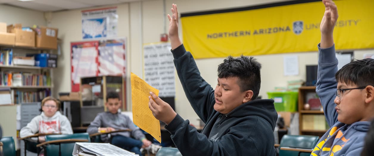 Students raising hands in a classroom with a Northern Arizona University banner in the background. Students raising hands in a classroom with a Northern Arizona University banner in the background.
