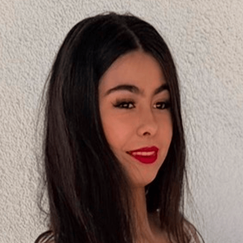 Person with long dark hair standing against a textured wall. Person with long dark hair standing against a textured wall.