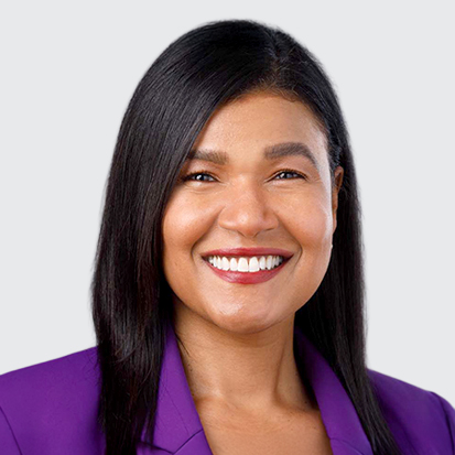 Person wearing a purple jacket with straight black shoulder-length hair against a grey background.