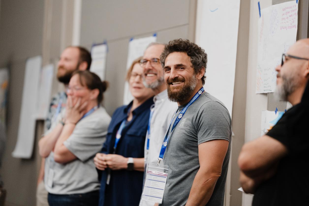 Group of people standing in a room with blurred faces and wearing conference badges. Group of people standing in a room with blurred faces and wearing conference badges.