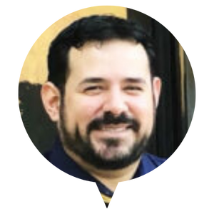 A person with short dark hair wearing a dark shirt.