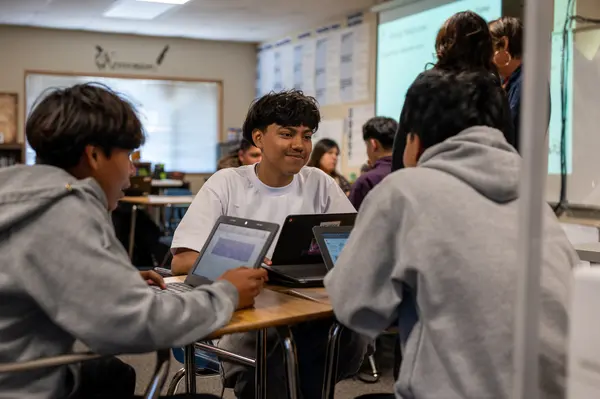 Students seated at desks working on laptops in a classroom setting. Students seated at desks working on laptops in a classroom setting.
