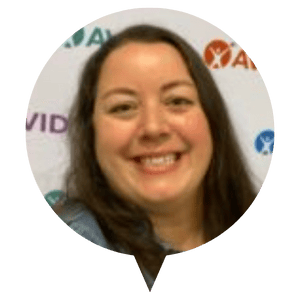 Individual with long, dark hair standing in front of a white backdrop featuring various logos. Individual with long, dark hair standing in front of a white backdrop featuring various logos.