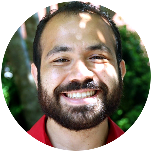 A blurred image of a person's head and neck set against an outdoor background.