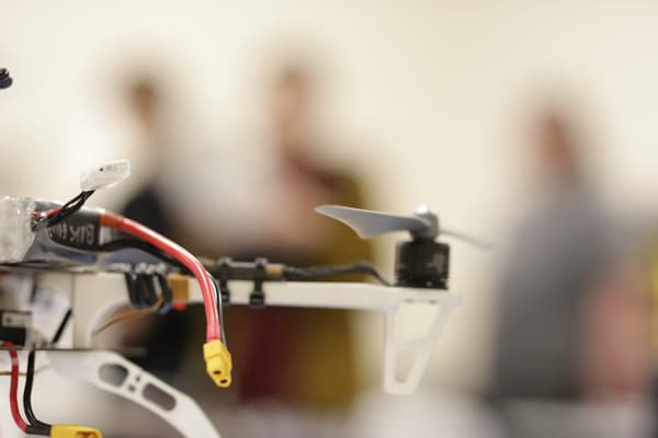 Close-up view of a drone with visible wires and a propeller, with blurred background. Close-up view of a drone with visible wires and a propeller, with blurred background.