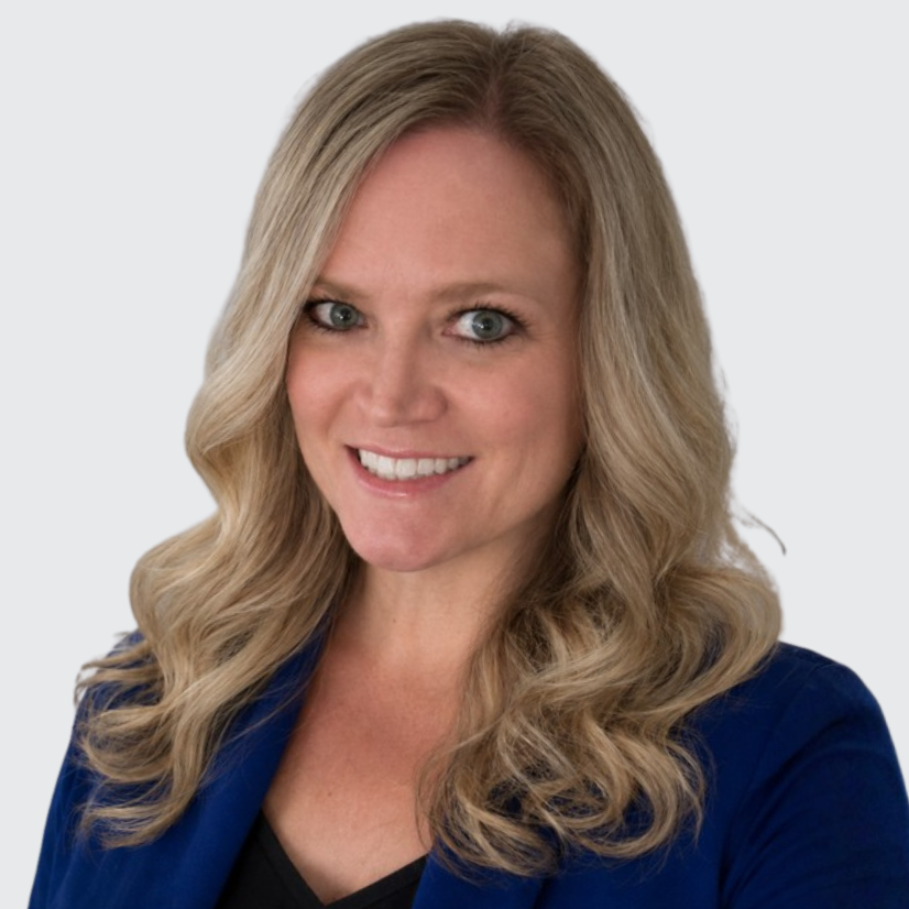 A person with long, wavy hair is smiling and wearing a dark blue blazer, set against a plain light background.