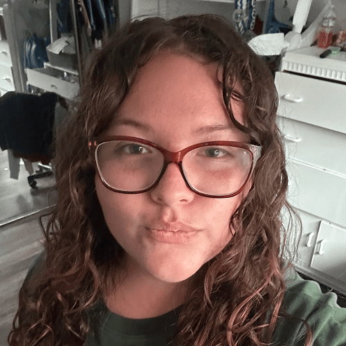 Image of a person with curly hair in a room with a reflection visible in the background mirror. Image of a person with curly hair in a room with a reflection visible in the background mirror.