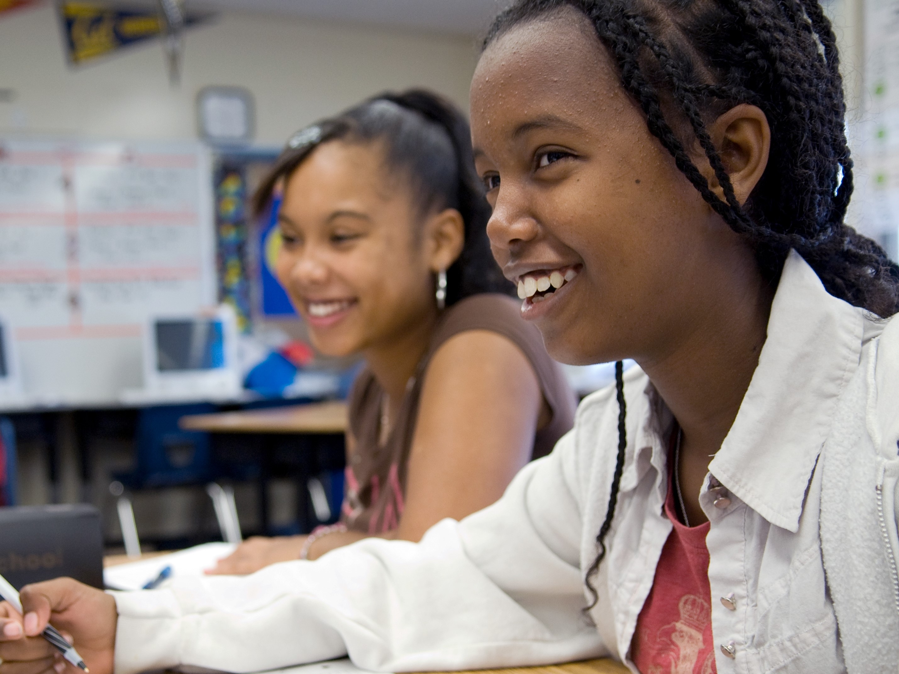 Two scholars sitting in a classroom setting, confidently engaging in their work.