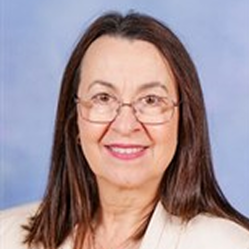 A person with medium-length straight hair wearing a light-colored jacket against a blue background.