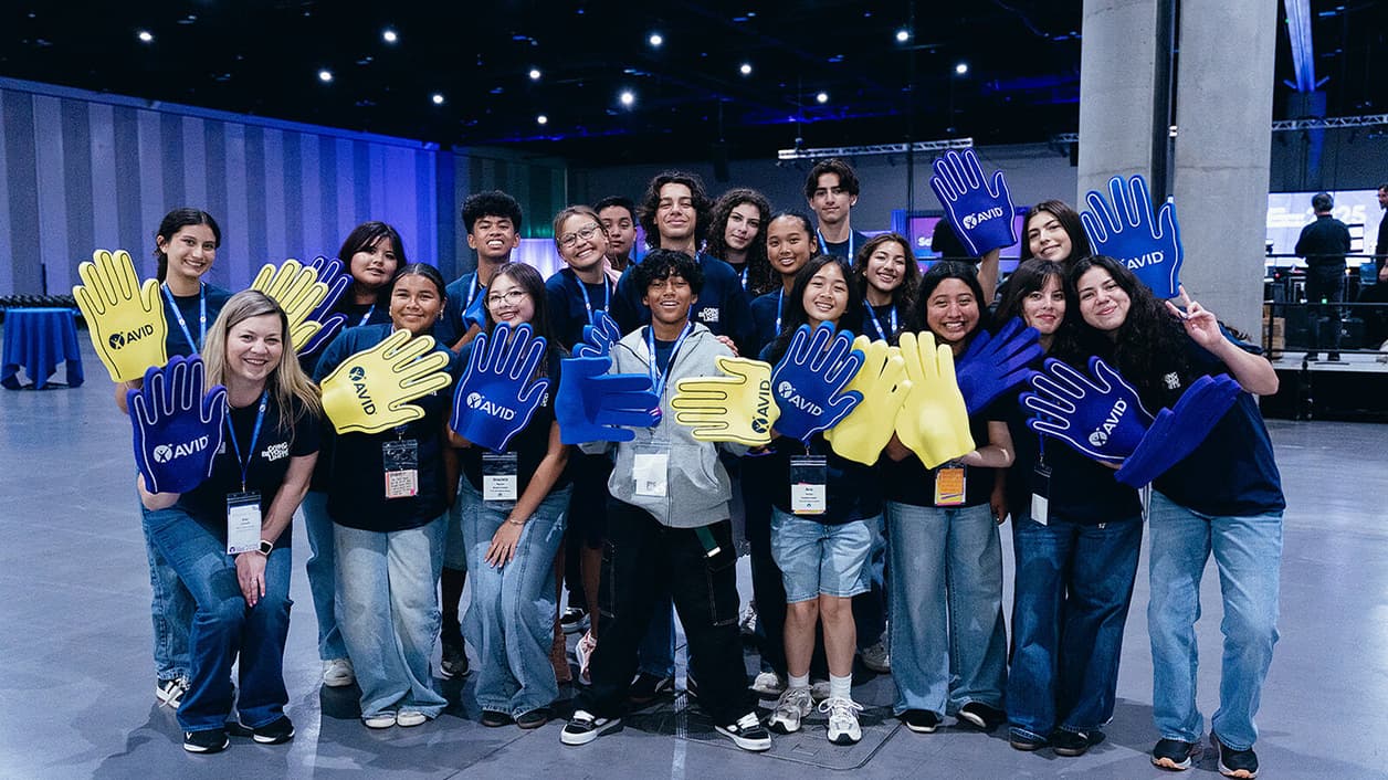 Group of people standing together, holding large blue and yellow foam hands in an indoor setting. Group of people standing together, holding large blue and yellow foam hands in an indoor setting.