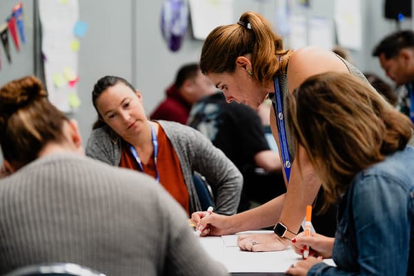 Group of people working together at a table during a collaborative activity in an indoor setting. Group of people working together at a table during a collaborative activity in an indoor setting.