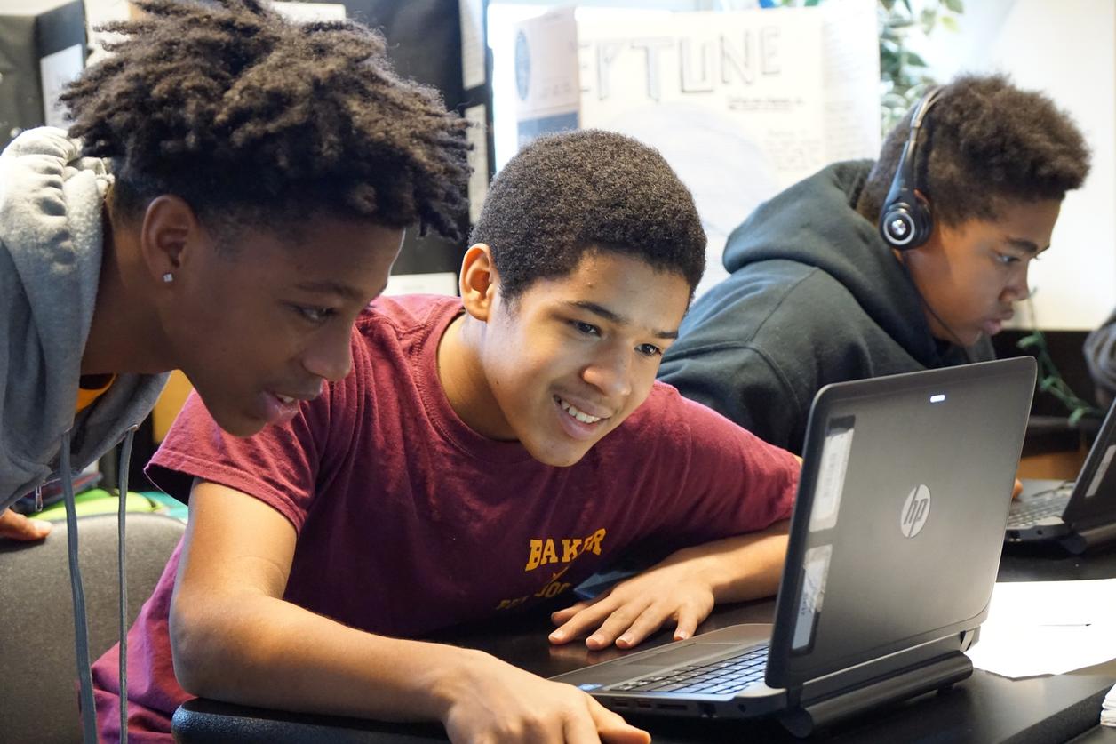 Three individuals working on laptops, one wearing headphones. Three individuals working on laptops, one wearing headphones.