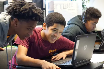 Three individuals working on laptops, one wearing headphones. Three individuals working on laptops, one wearing headphones.