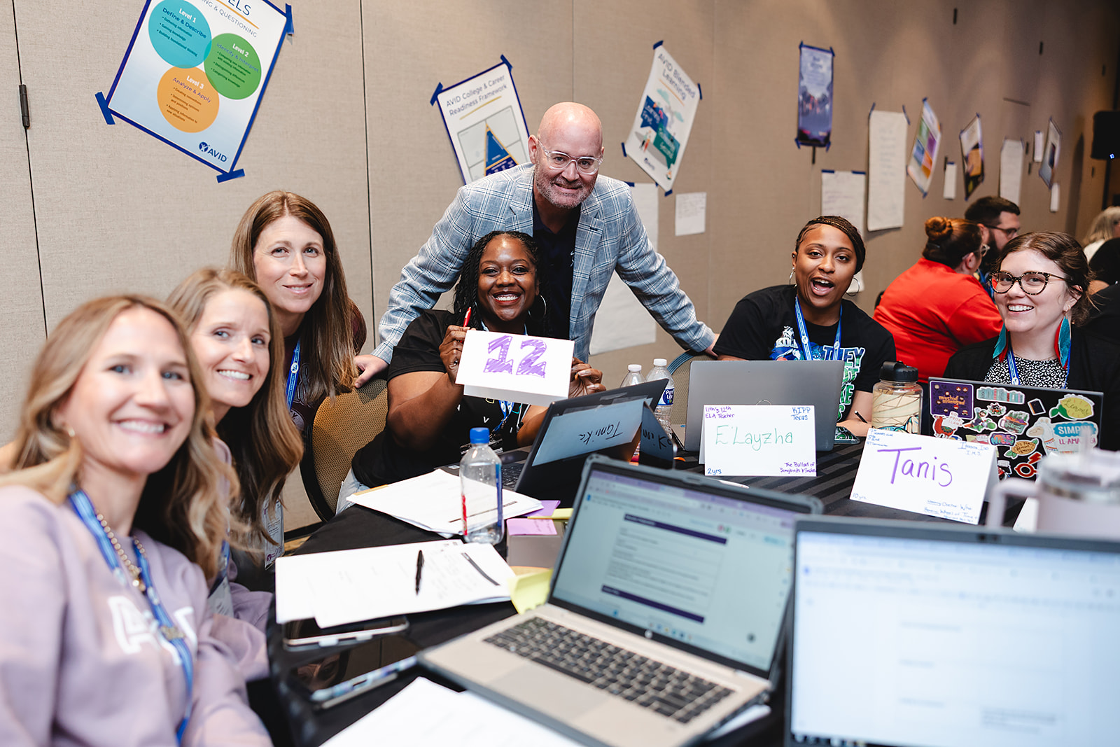 A group of people collaborating around a table with laptops and notes in a conference room.