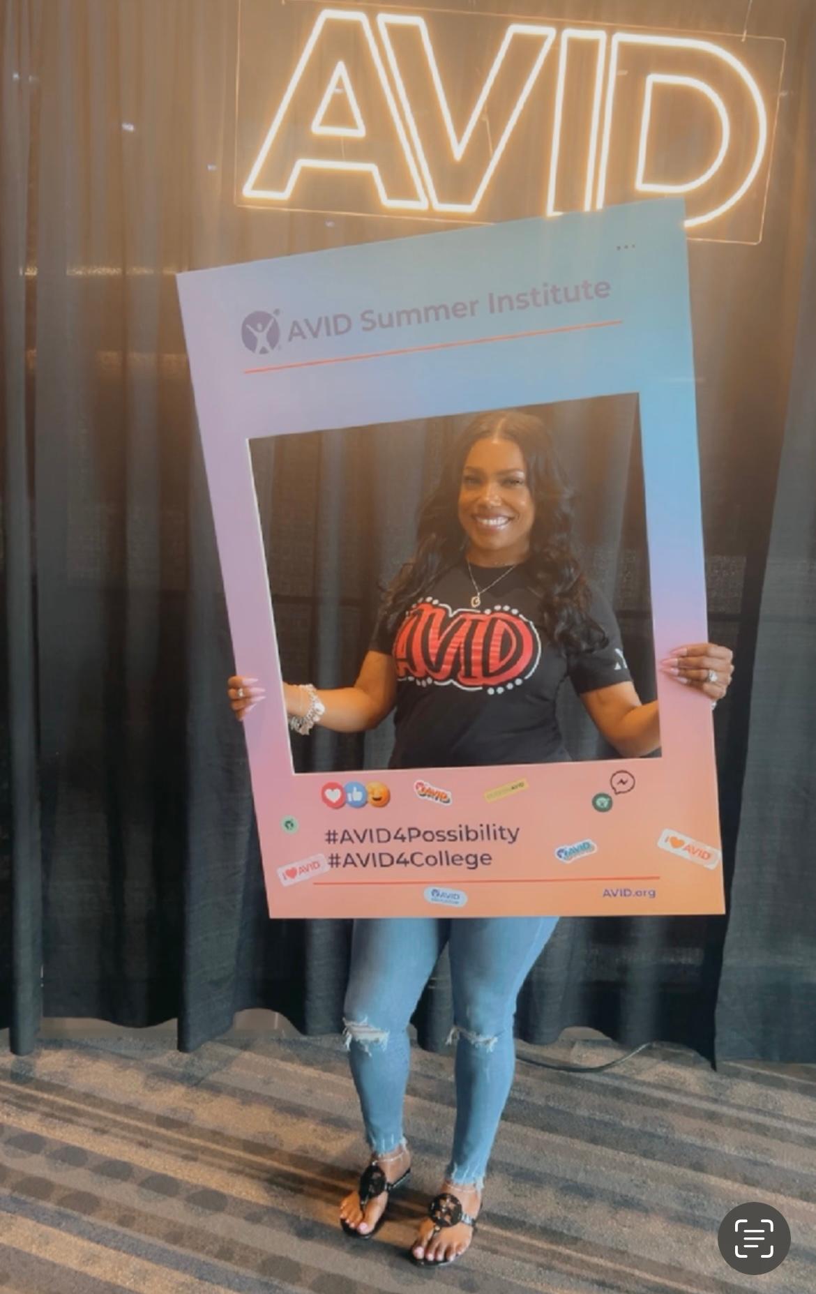 Individual holding a frame with AVID Summer Institute branding, in front of an AVID sign. Individual holding a frame with AVID Summer Institute branding, in front of an AVID sign.