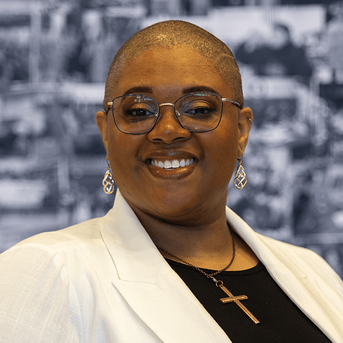 Person wearing a white jacket and black shirt with a cross necklace, background is blurred. Person wearing a white jacket and black shirt with a cross necklace, background is blurred.