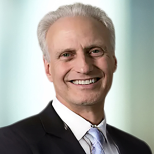 A person dressed in a suit and tie with a light background.