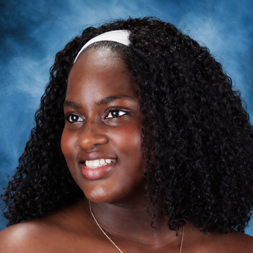 Person with curly hair, wearing a white headband, against a blue background.