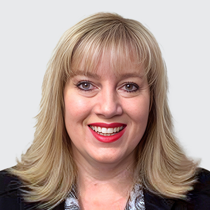 A professional individual with blonde hair wearing a black blazer and patterned shirt.