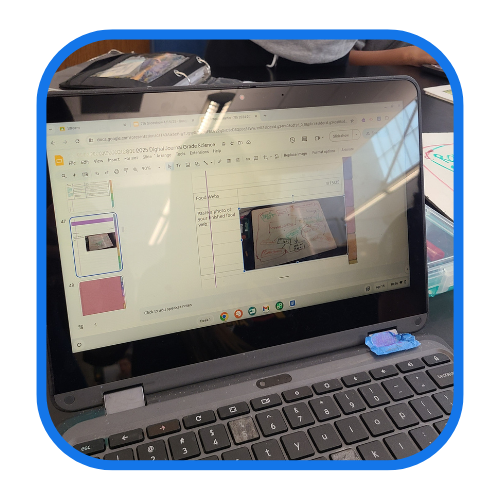 Image showing a laptop screen displaying a presentation with a diagram, held open in a web browser. The laptop has a few items placed on the keyboard.