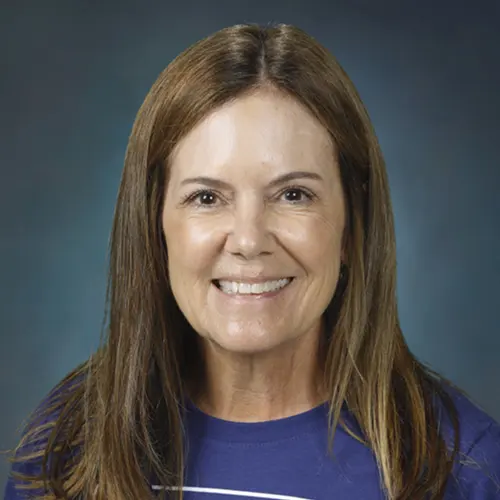 An individual with long, straight hair wearing a blue shirt, with the face blurred against a dark blue background An individual with long, straight hair wearing a blue shirt, with the face blurred against a dark blue background