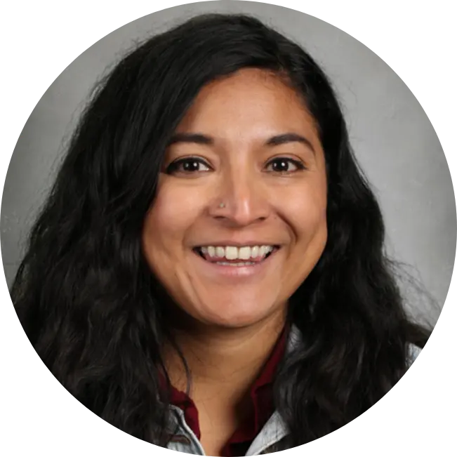 A person with long dark hair smiles in a centered headshot against a gray background. A person with long dark hair smiles in a centered headshot against a gray background.