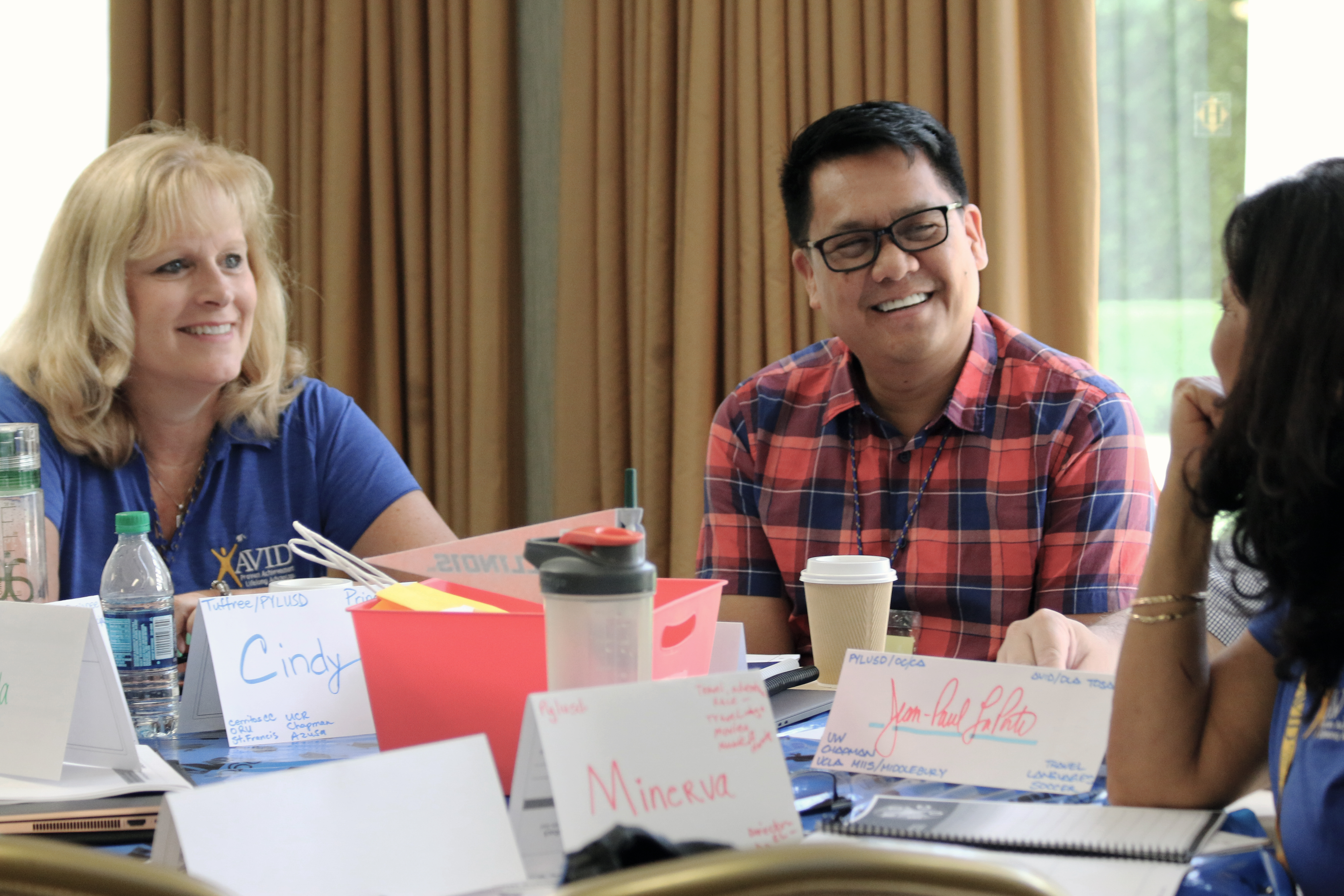 Group of people sitting around a table with name tags and water bottles in a meeting room.