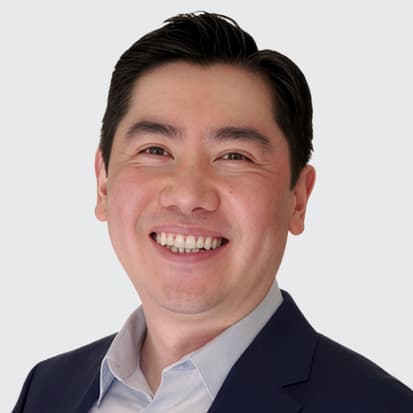 A headshot of a person with short, dark hair, wearing a formal suit jacket and a light-colored collared shirt, against a plain white background. A headshot of a person with short, dark hair, wearing a formal suit jacket and a light-colored collared shirt, against a plain white background.