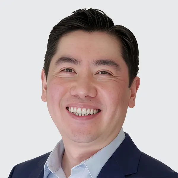 A headshot of a person with short, dark hair, wearing a formal suit jacket and a light-colored collared shirt, against a plain white background. A headshot of a person with short, dark hair, wearing a formal suit jacket and a light-colored collared shirt, against a plain white background.