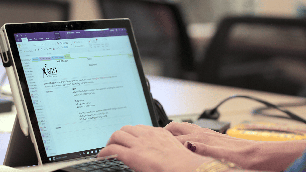 Close-up of hands typing on a tablet keyboard with AVID notes displayed on the screen. Close-up of hands typing on a tablet keyboard with AVID notes displayed on the screen.