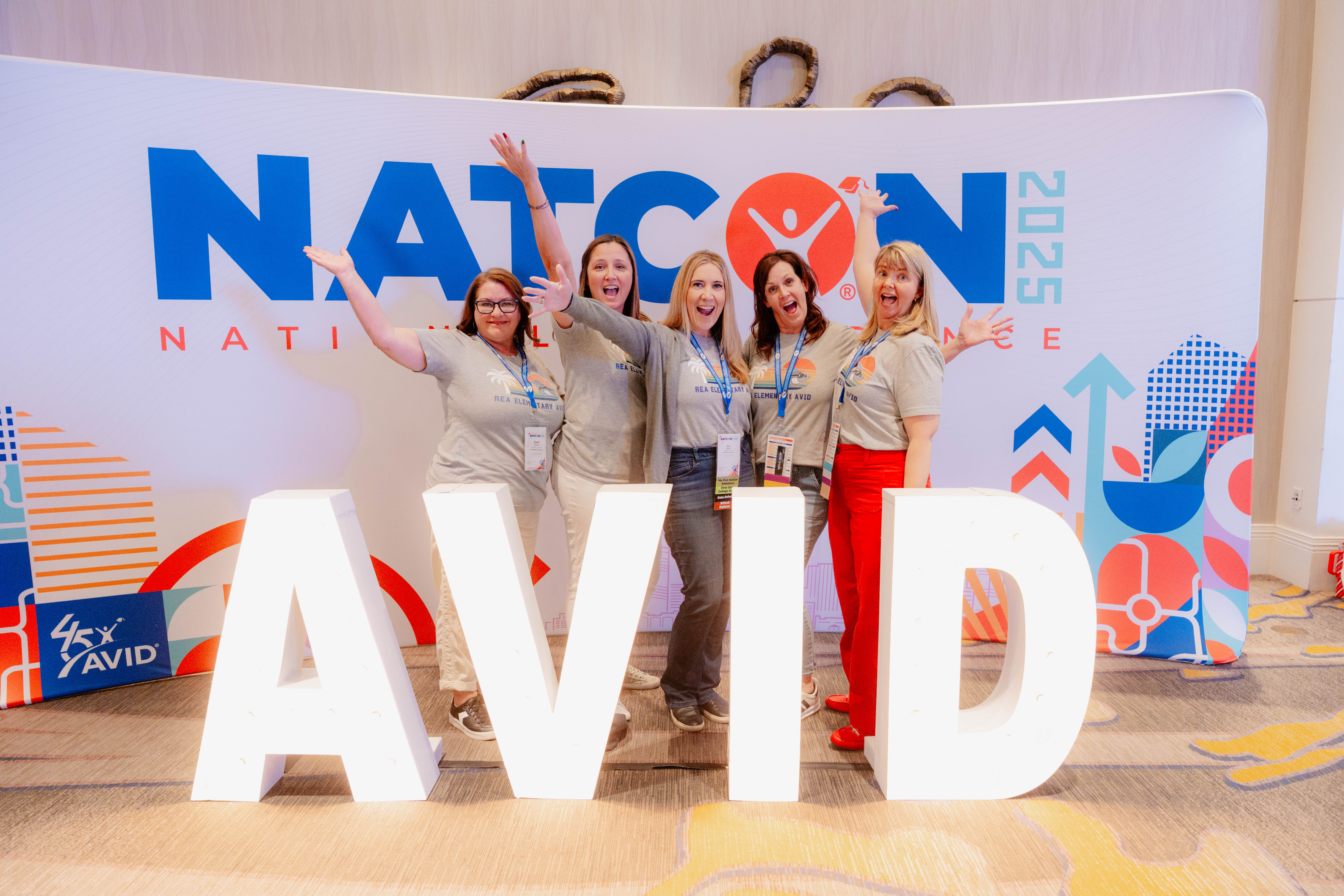 Group of people posing in front of a NATCON 2025 sign with large illuminated AVID letters.