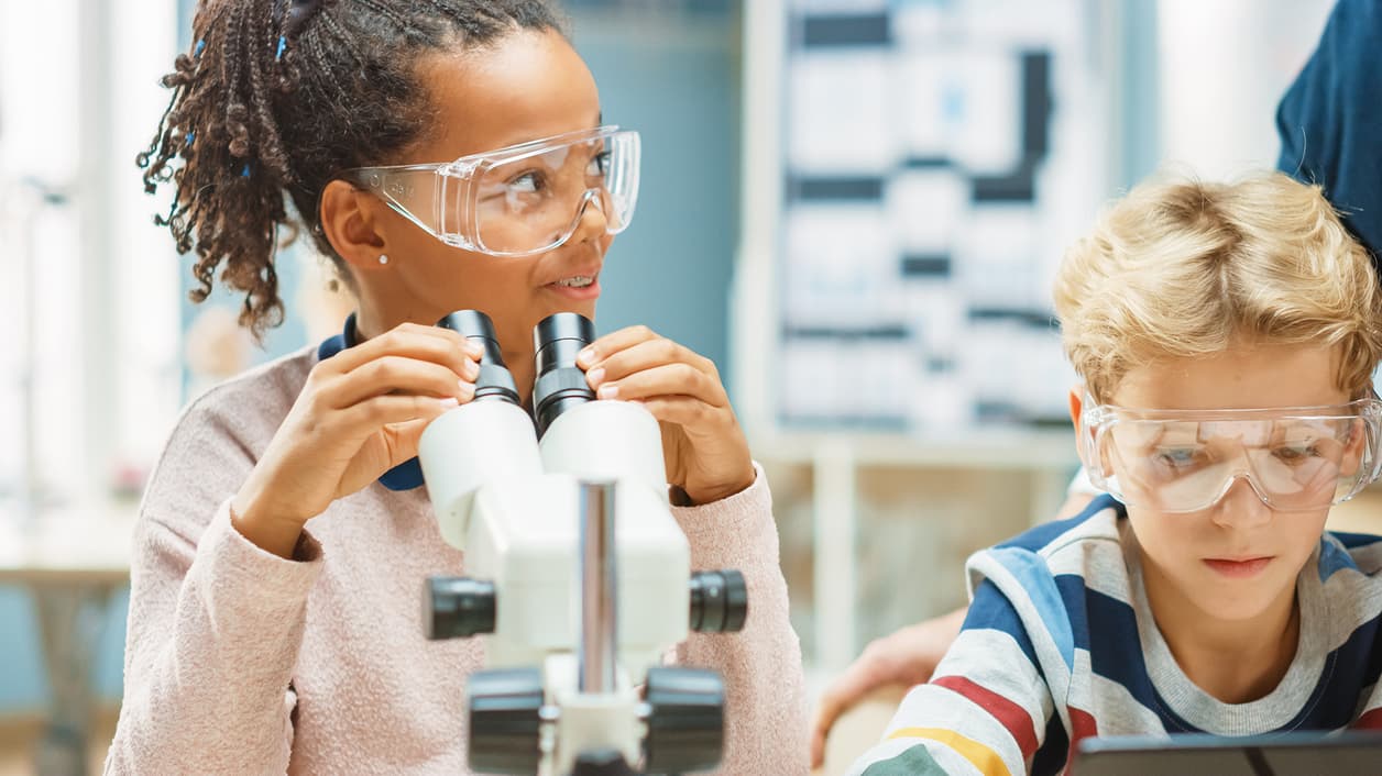 Children exploring with a microscope and tablet in a classroom setting. Children exploring with a microscope and tablet in a classroom setting.