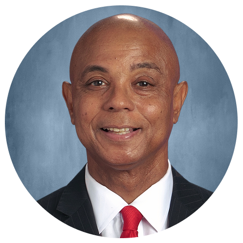 A person wearing a suit and a red tie against a grey background.