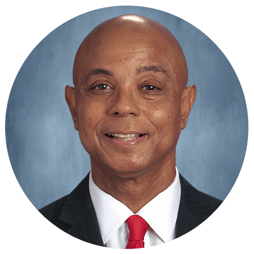 A person wearing a suit and a red tie against a grey background. A person wearing a suit and a red tie against a grey background.