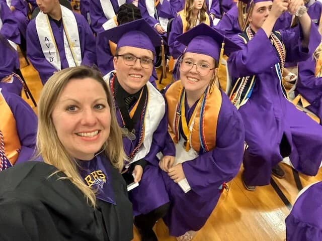 Students wearing purple graduation gowns and caps sitting together. Students wearing purple graduation gowns and caps sitting together.