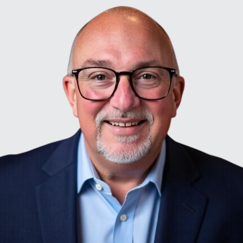 A smiling person wearing glasses and a blue suit jacket.