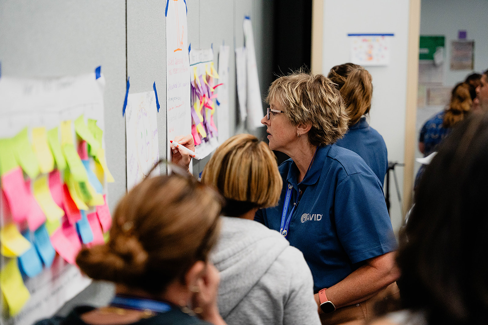 Group of people participating in a collaborative activity involving sticky notes on a wall.